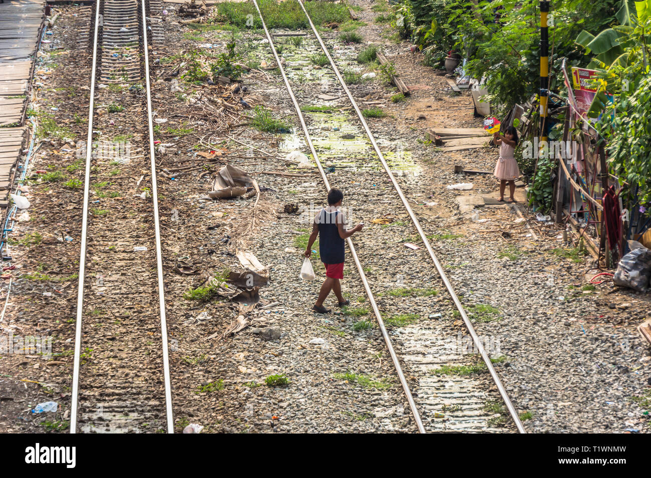 Un garçon marche à une fille de fer de passage à Bangkok, Thaïlande Banque D'Images