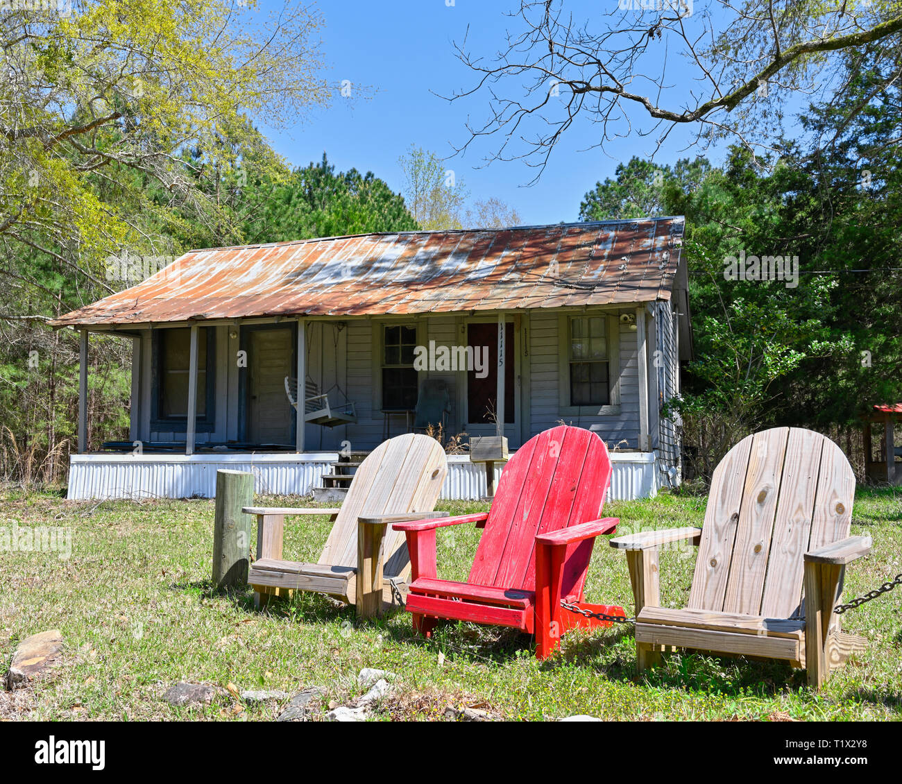 Petite cabane dans les régions rurales de l'Alabama avec trois chaises en bois dans la cour avant montrant la vie de campagne ou le mode de vie dans le sud. Banque D'Images