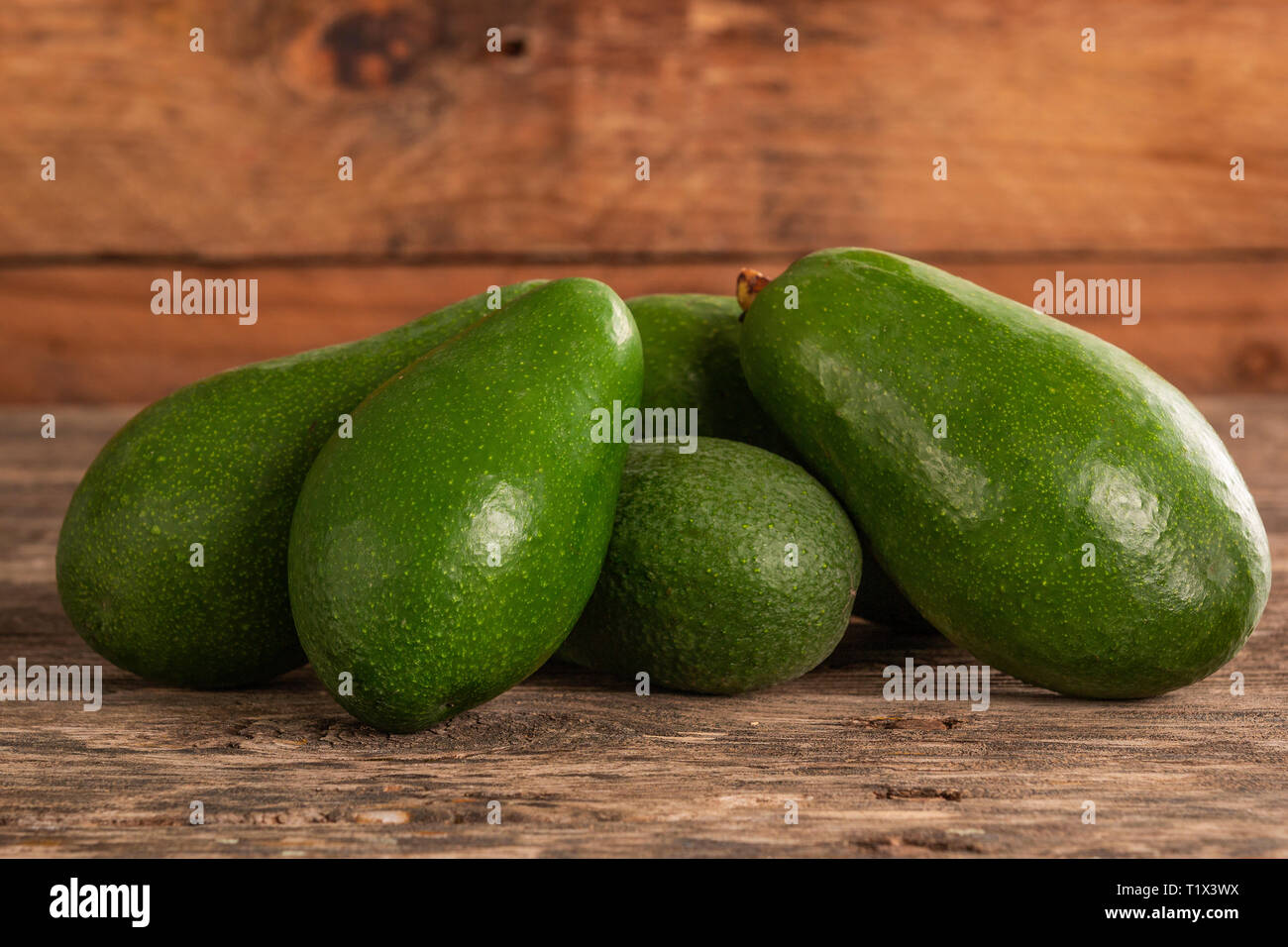 Pile d'éplucher les avocats d'un vert vif sur table rustique en bois Banque D'Images