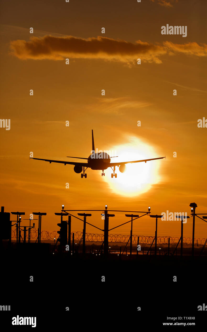 Atterrissage avion à l'aéroport d'Heathrow au coucher du soleil Banque D'Images