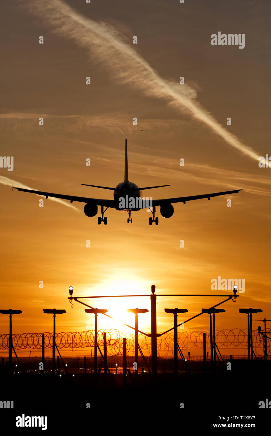 Atterrissage avion à l'aéroport d'Heathrow au coucher du soleil Banque D'Images