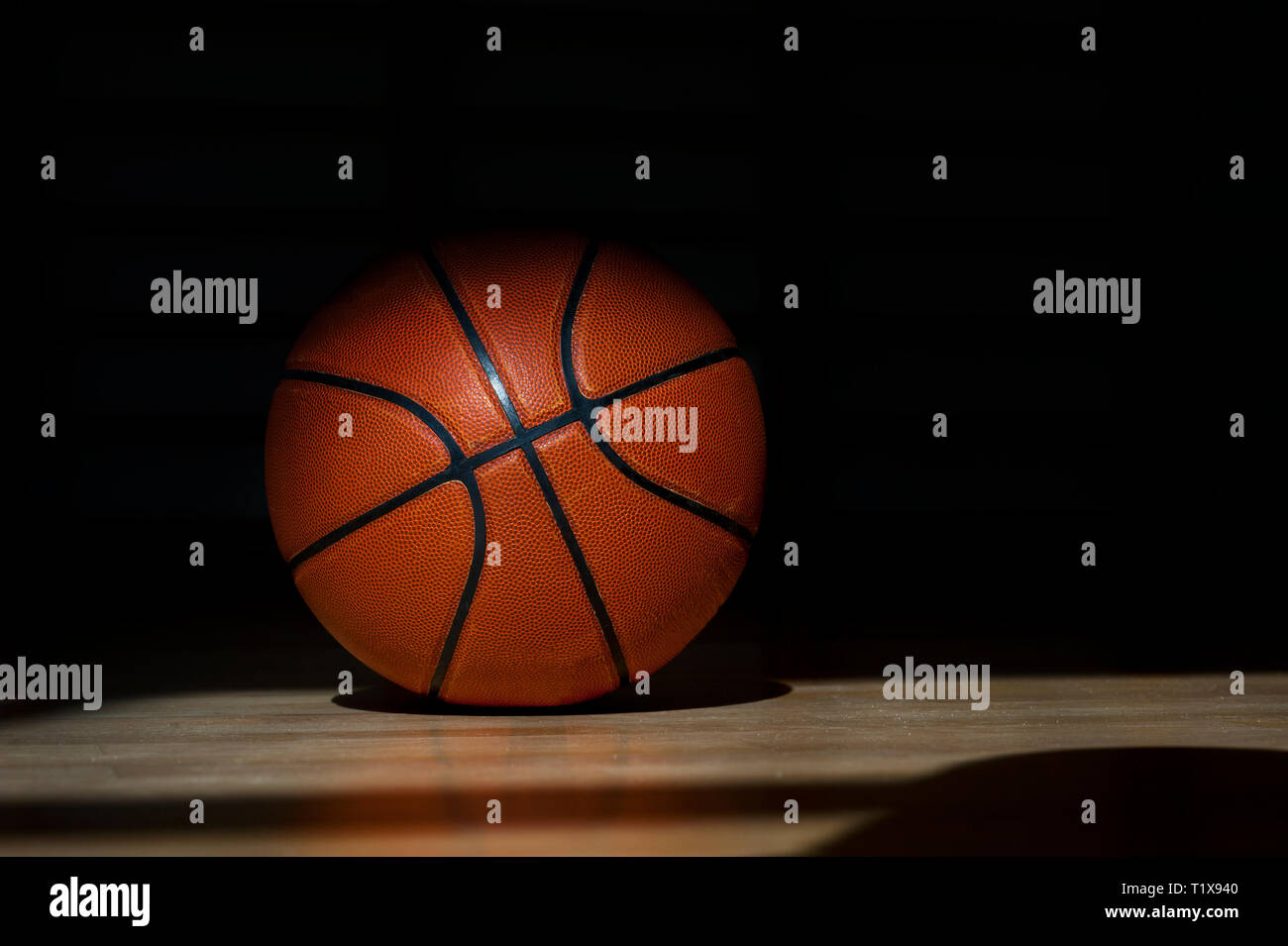 Ballon de basket-ball sur le plancher avec fond noir Banque D'Images