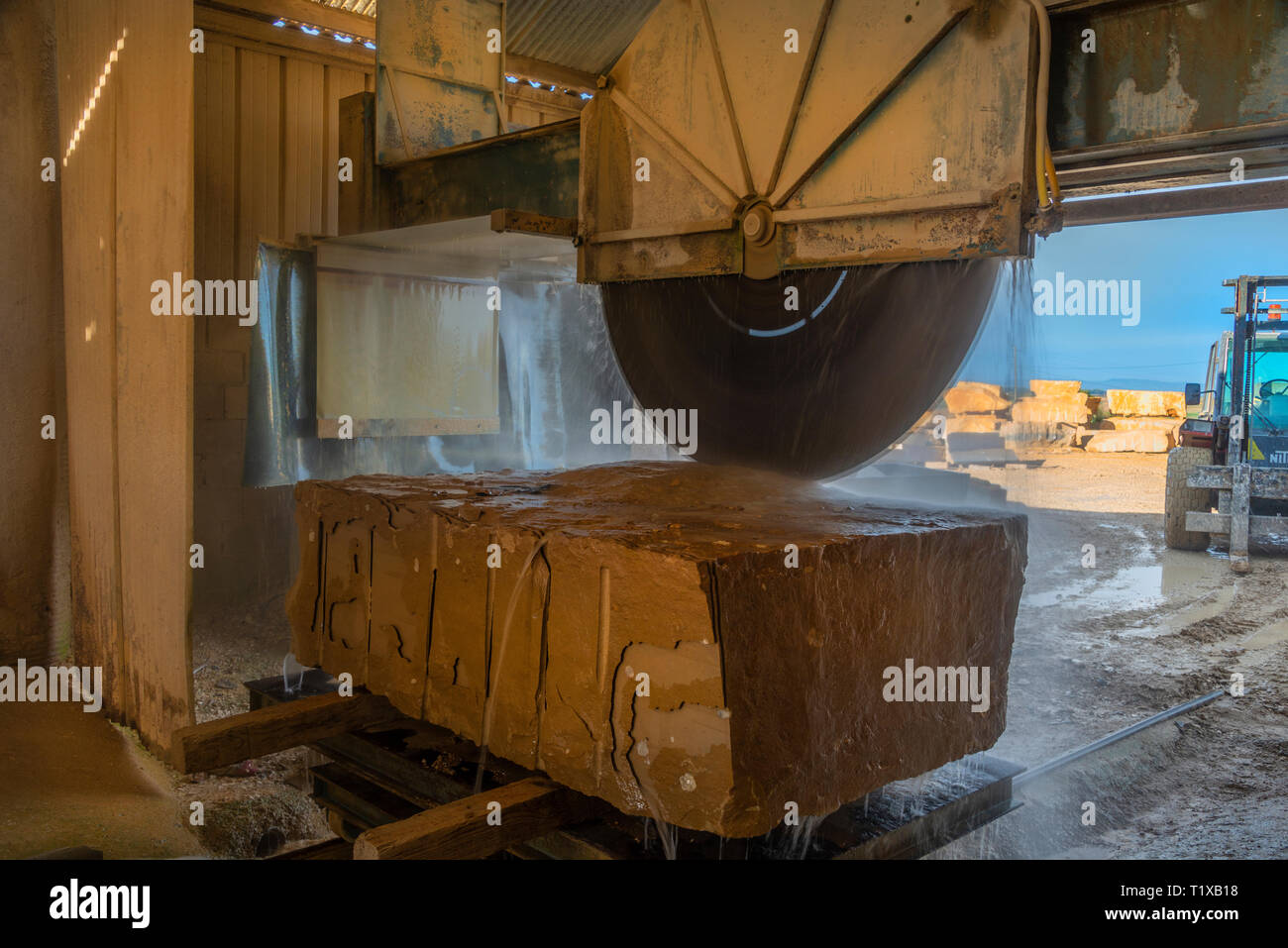 Machine de découpe de la pierre à l'œuvre à une carrière de calcaire. D'être coupé avec une grande scie circulaire, tandis que l'eau pulvérisée refroidit le disque. Banque D'Images