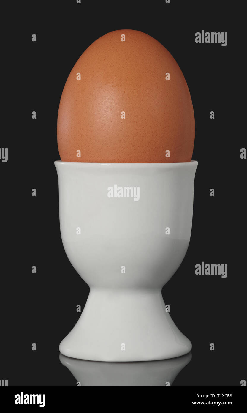 Oeuf de poule à Egg Cup isolé sur fond noir Banque D'Images