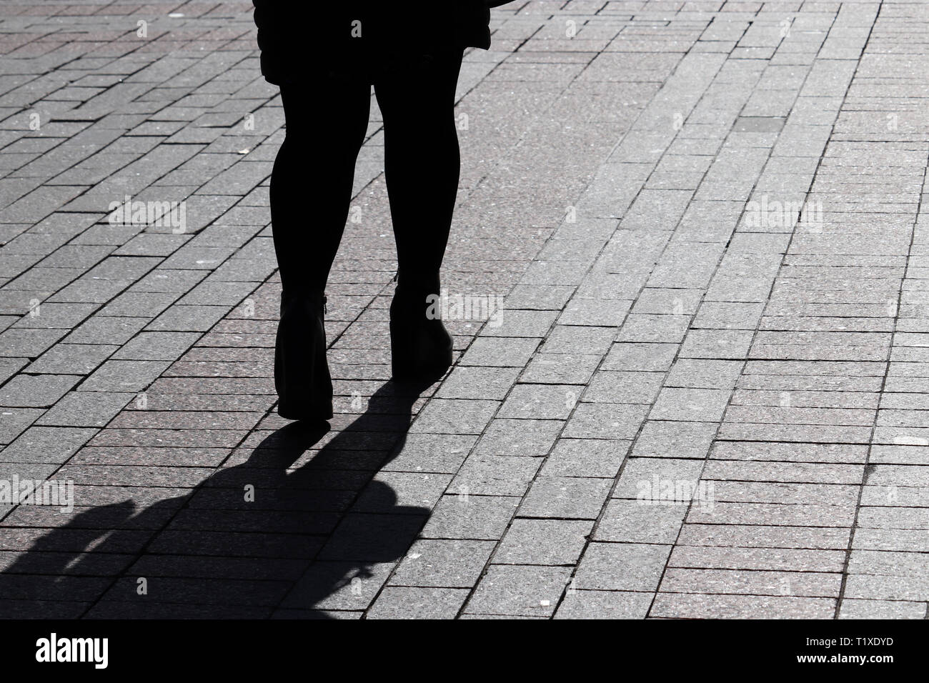 Silhouette de femme seule dans la rue, l'ombre noire sur la chaussée. Les jambes des femmes sur le trottoir, concept de la solitude, la séparation, l'alimentation Banque D'Images
