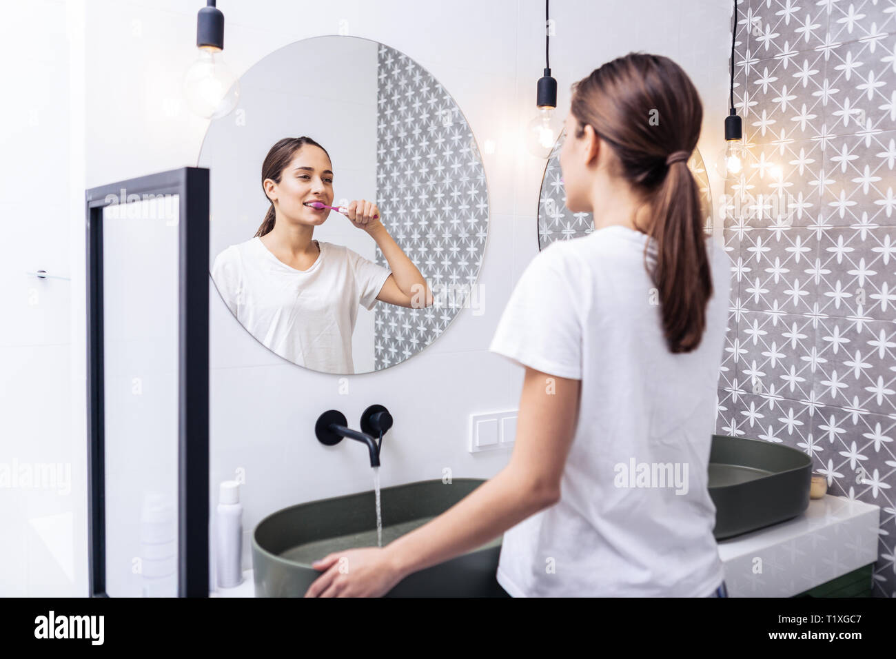 Femme séduisante se brosser les dents, debout dans la salle de bains Banque D'Images