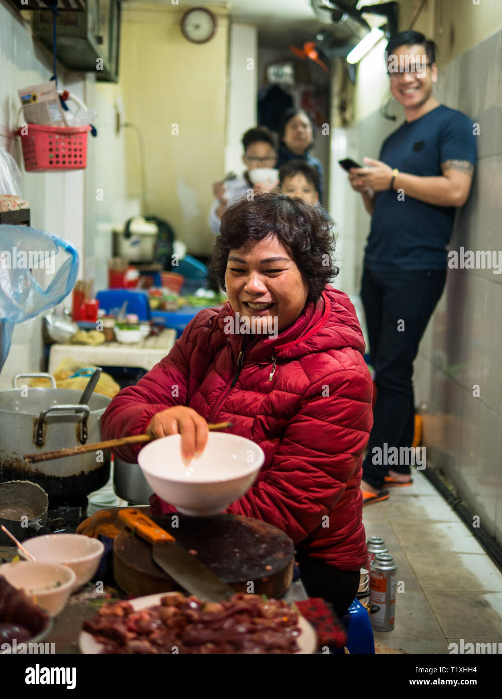 Vietnamienne de la préparation des aliments de rue avec sa famille dans un petit magasin du marché, Hanoi, Vietnam Banque D'Images