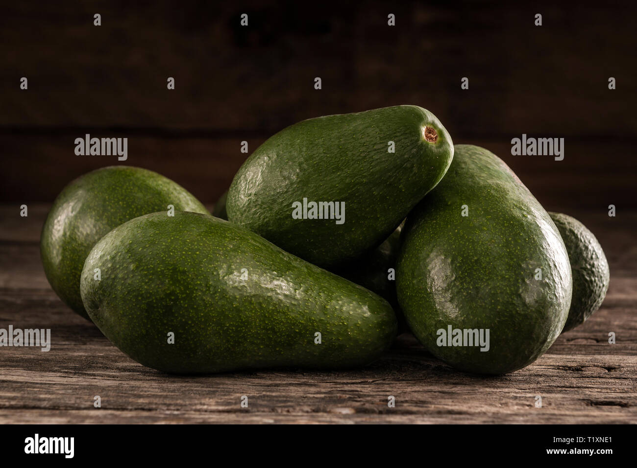 Pile d'éplucher les avocats d'un vert vif sur table rustique en bois Banque D'Images
