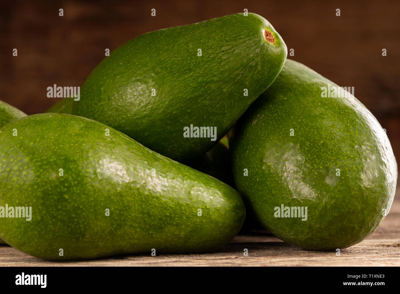 Pile d'éplucher les avocats d'un vert vif sur table rustique en bois Banque D'Images