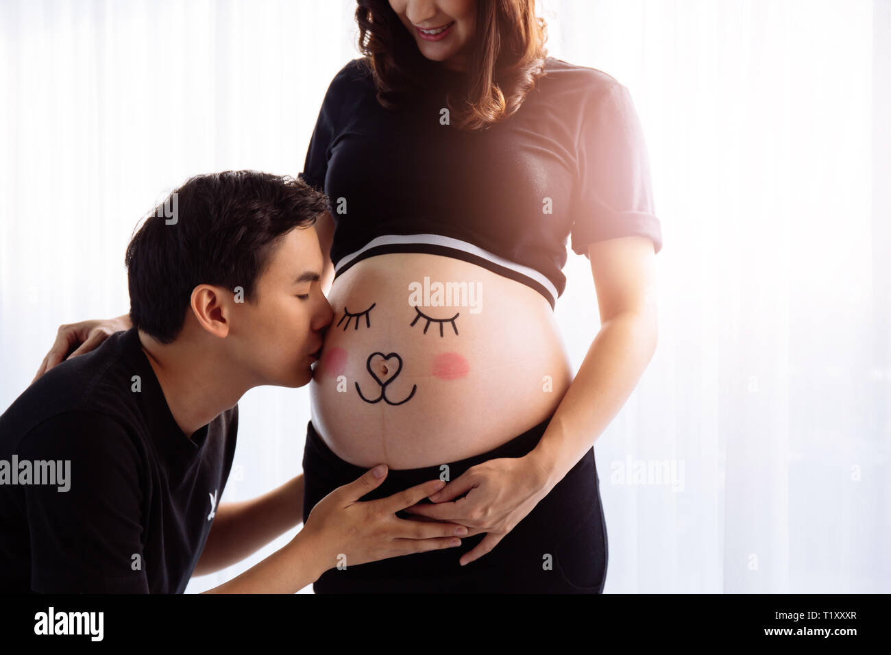 Les jeunes époux, baiser sur le ventre de femme enceinte de dessin avec soin. Banque D'Images