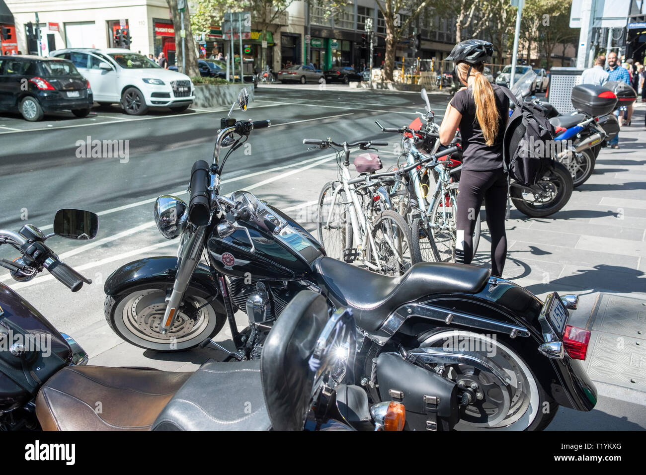 Parcs de banlieue fille son vélo à côté des motos sur le trottoir dans le centre-ville de Melbourne, Victoria, Australie Banque D'Images