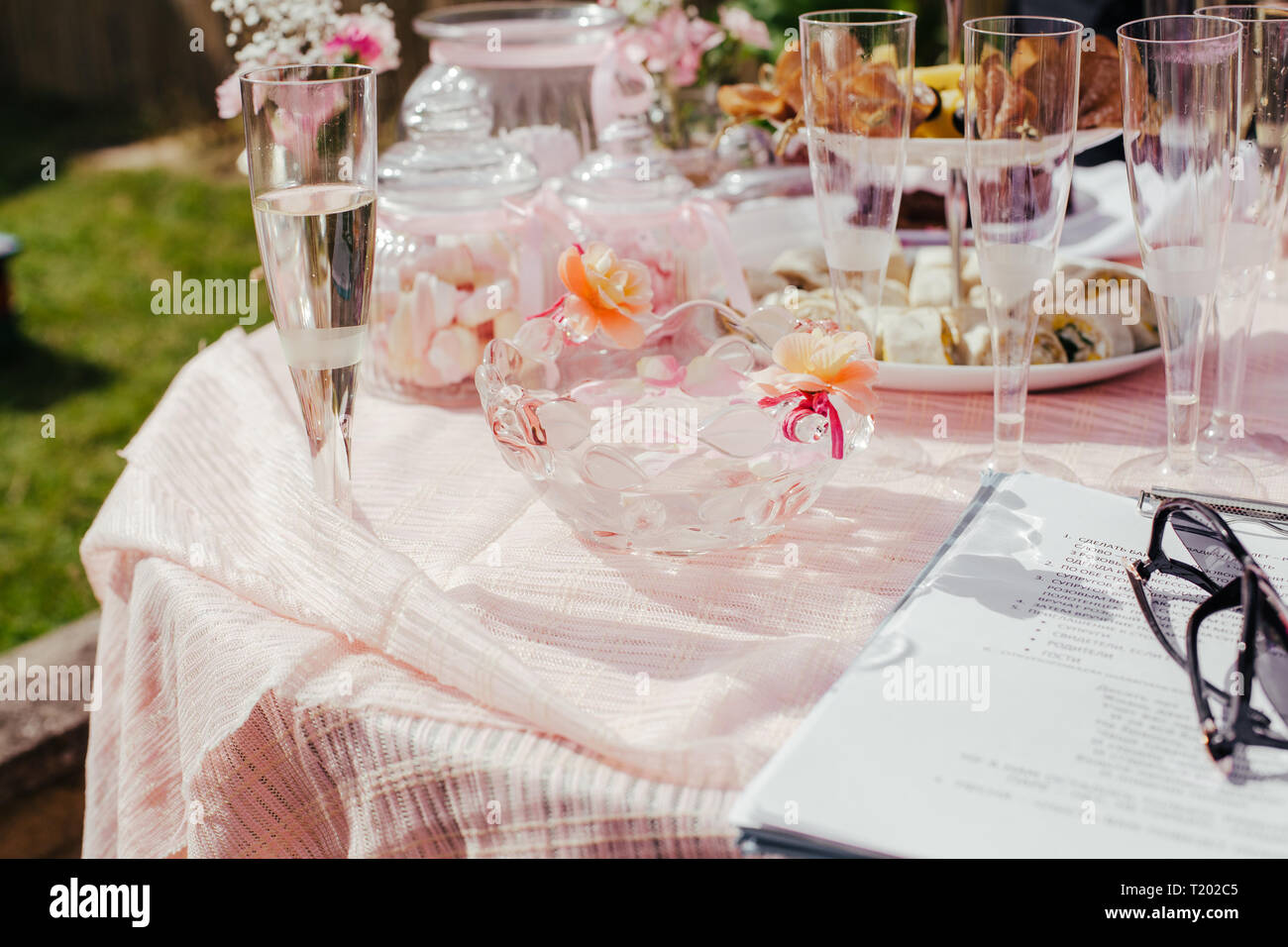 Table Bonbons, friandises dans le pot en verre, décor rose sur la table à l'extérieur en été. Table de travail avec de la nourriture, des canapés, des en-cas. Partie de la planification et de l'ordinateur portable, Banque D'Images
