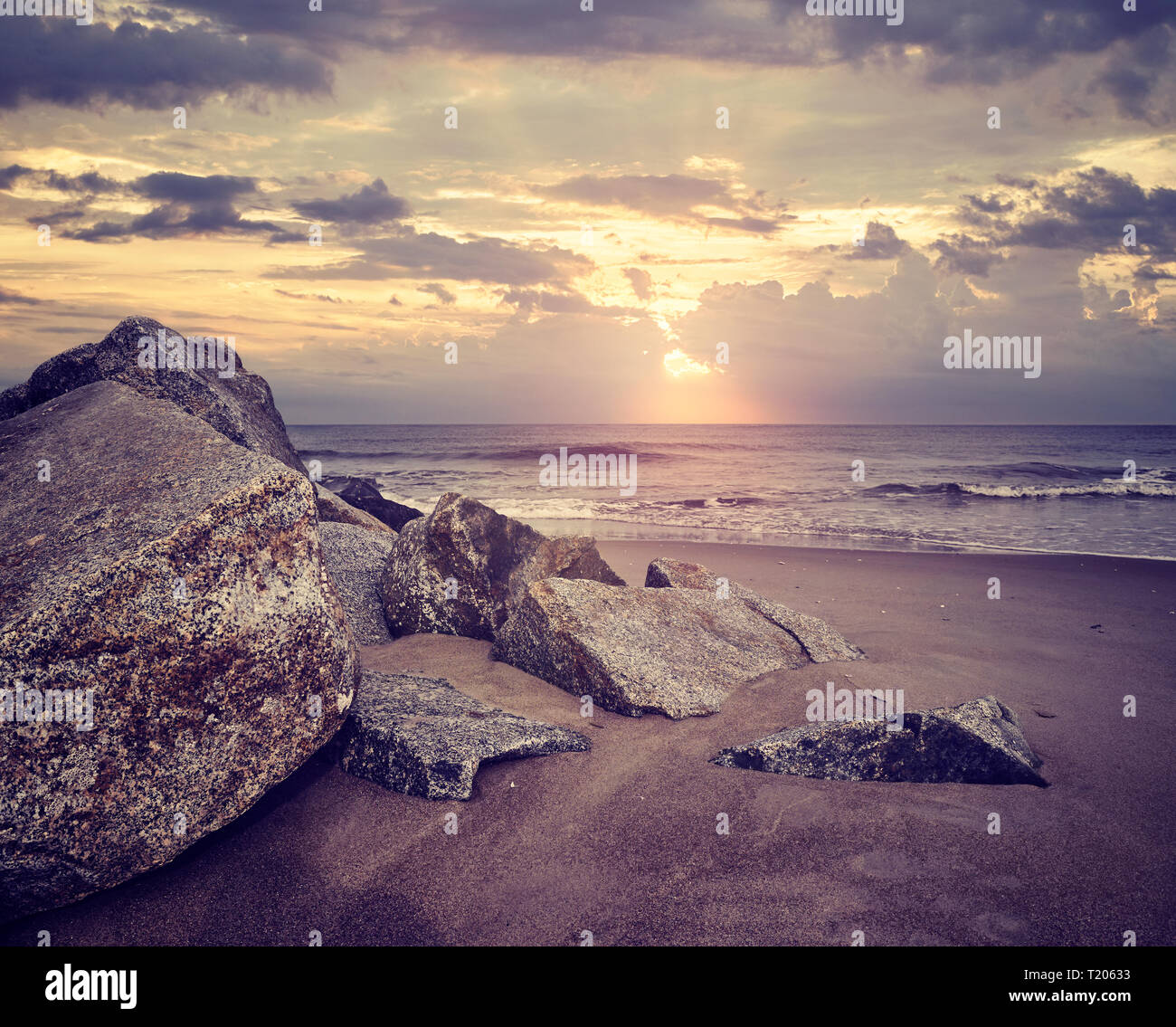Superbe coucher de soleil sur une plage de rochers, tons de couleur photo. Banque D'Images