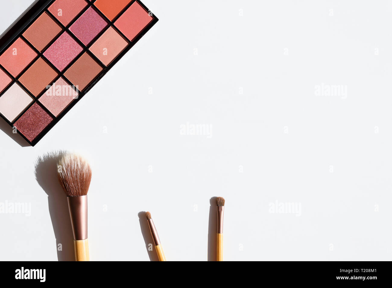 Vue de dessus de l'ombre d'oeil palette et pinceaux maquillage avec manches en bois. Les cosmétiques et les accessoires avec copie espace sur fond blanc. Banque D'Images