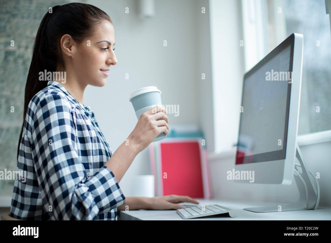 Femme travaillant à l'ordinateur à partir de la Tasse à emporter réutilisables Banque D'Images