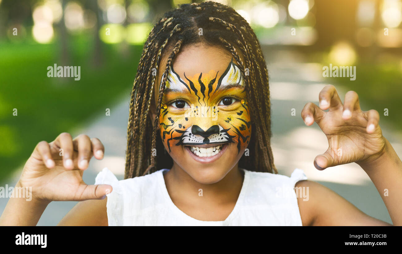 Adorable african-American Girl with creative face painting roaring Banque D'Images