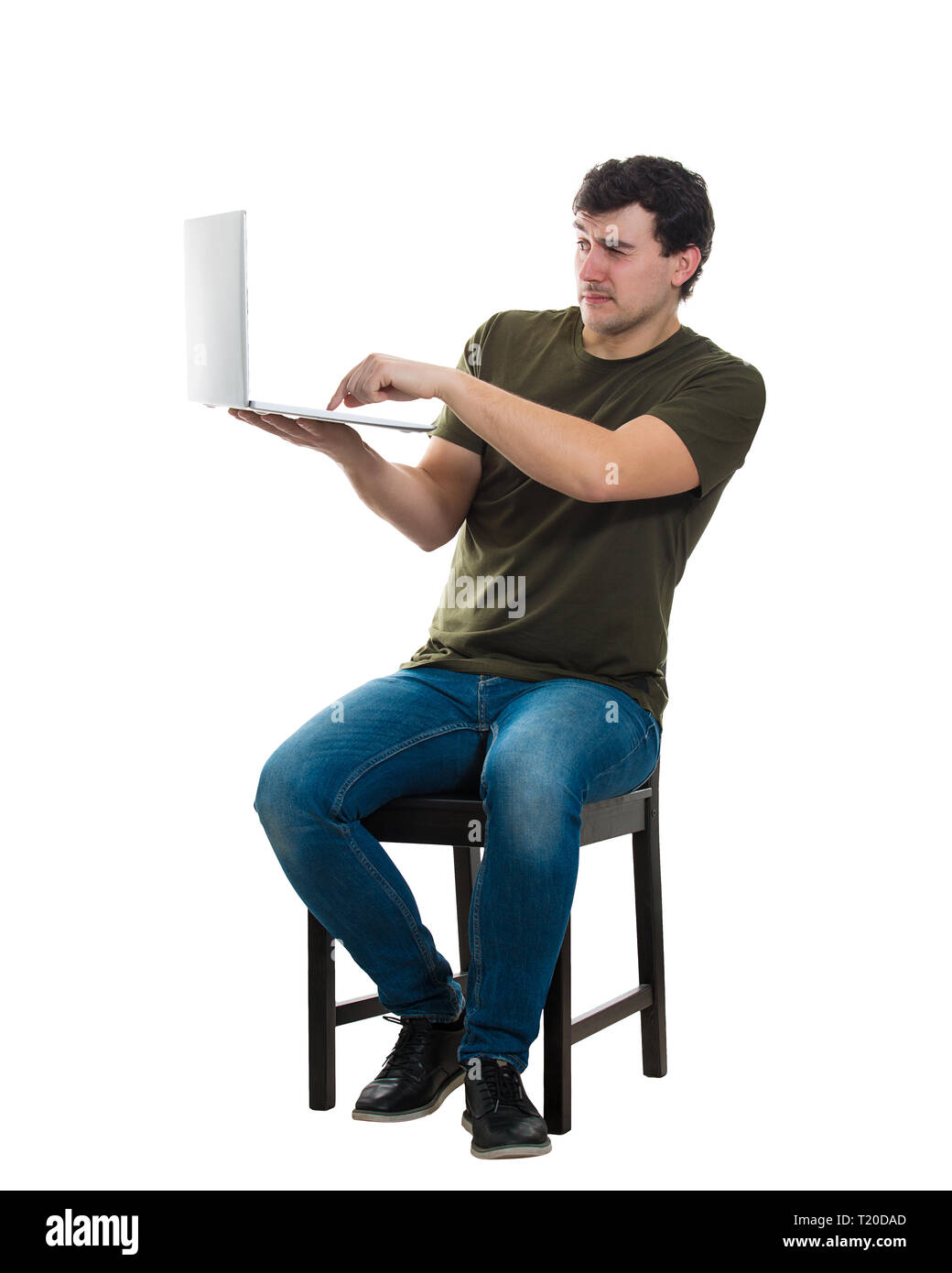 Jeune homme effrayé programmeur freelance ou assis sur une chaise en tenant son ordinateur portable en appuyant sur un bouton sur le clavier, pleine longueur portrait isolé sur fond blanc Banque D'Images