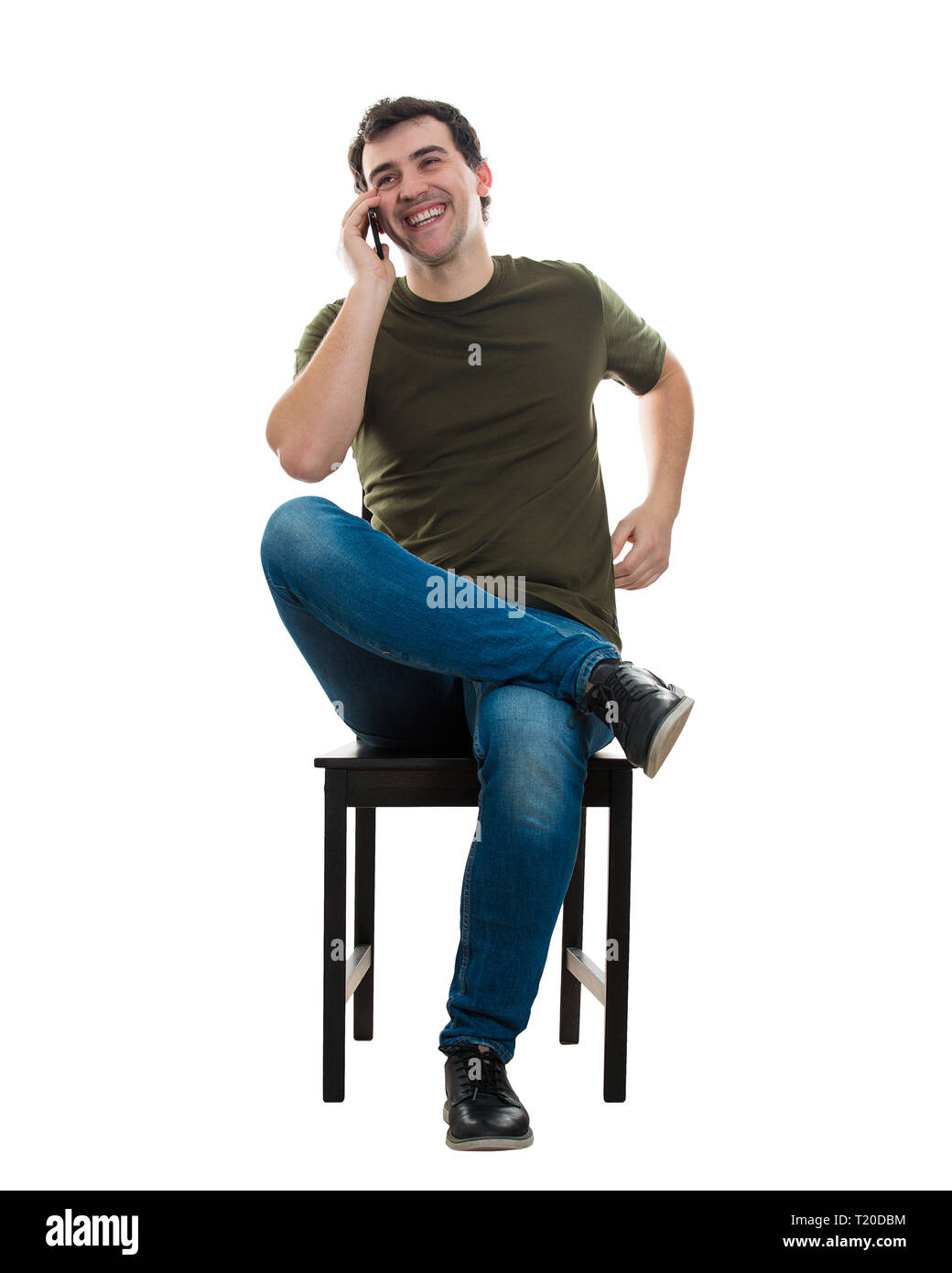 Portrait, cheerful casual young man assis sur une chaise smiling while talking on mobile phone isolé sur fond blanc. Heureux Détendu Banque D'Images