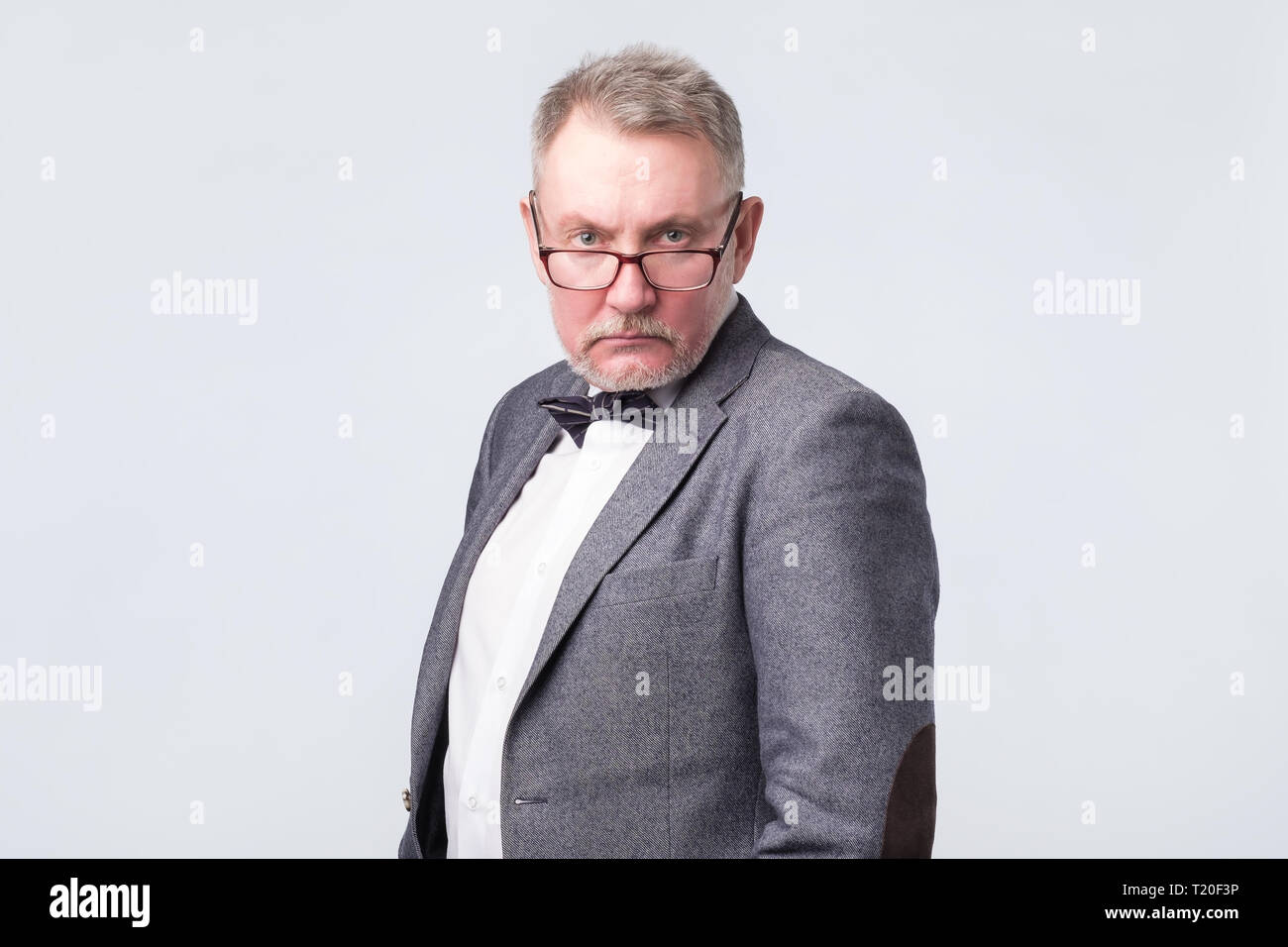 Vieil homme en costume et lunettes looking at camera avec confiance. Shoot Studio. Banque D'Images