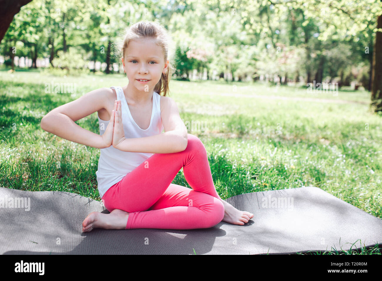 Belle Fille Est Assis Sur Carimate Dans Une Pose De Yoga Elle A Traverse Ses Jambes Mais Elle Est De Garder Ses Mains Ensemble Bebe Est A La Recherche D Appareil Photo Elle