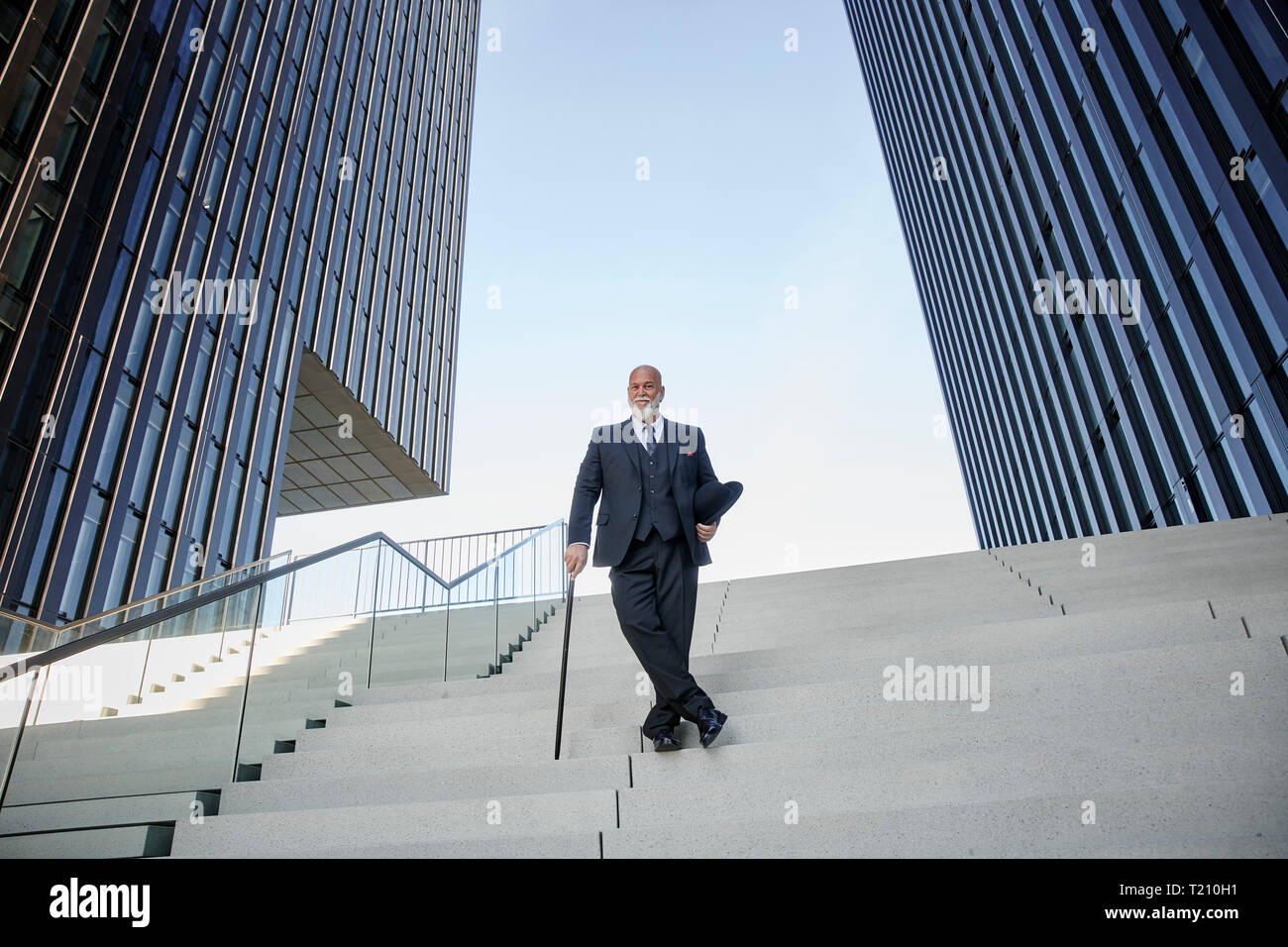 Elegant businessman avec chapeau melon et canne, debout dans les escaliers dans la ville Banque D'Images