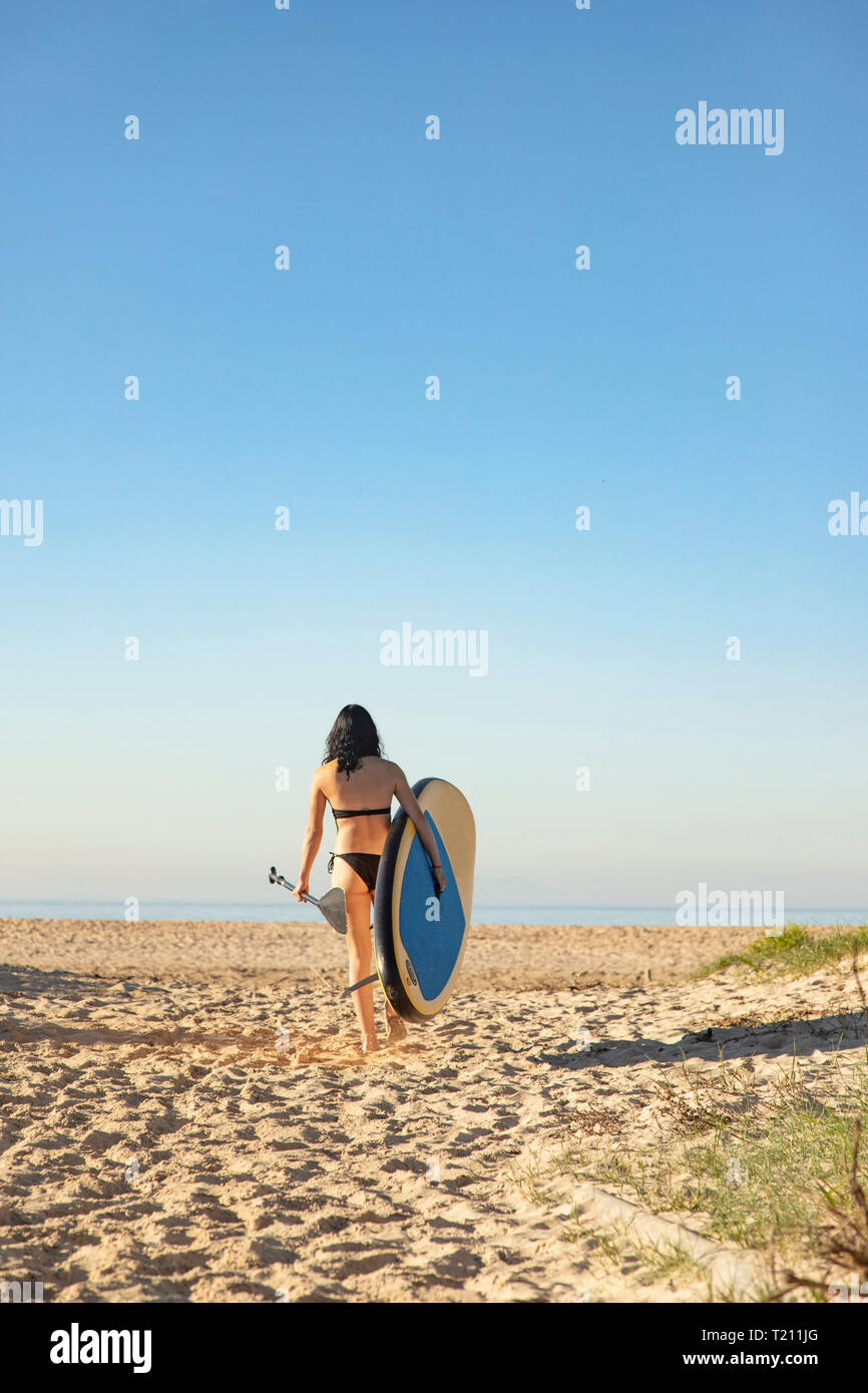 Espagne, Andalousie, Tarifa, woman walking with stand up paddle board sur la plage Banque D'Images
