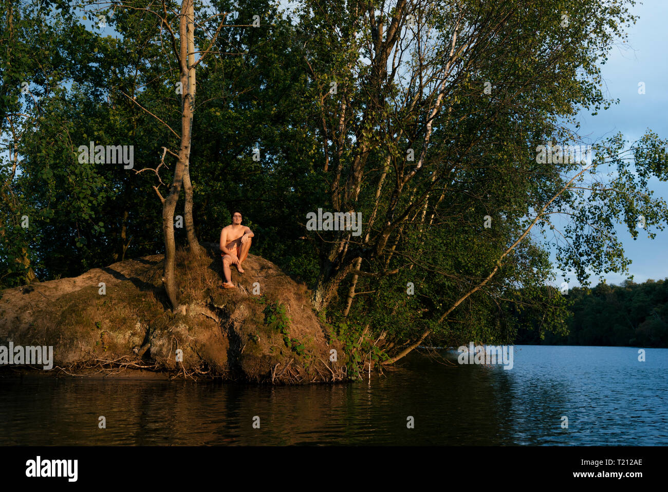 Homme assis sur une île dans un lac Banque D'Images