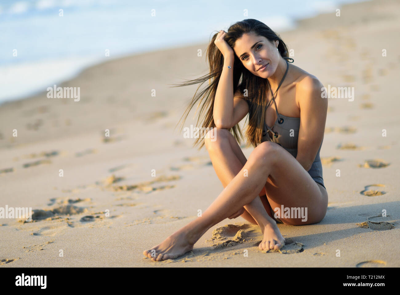 Magnifique Portrait de femme portant maillot assis sur la plage Banque D'Images