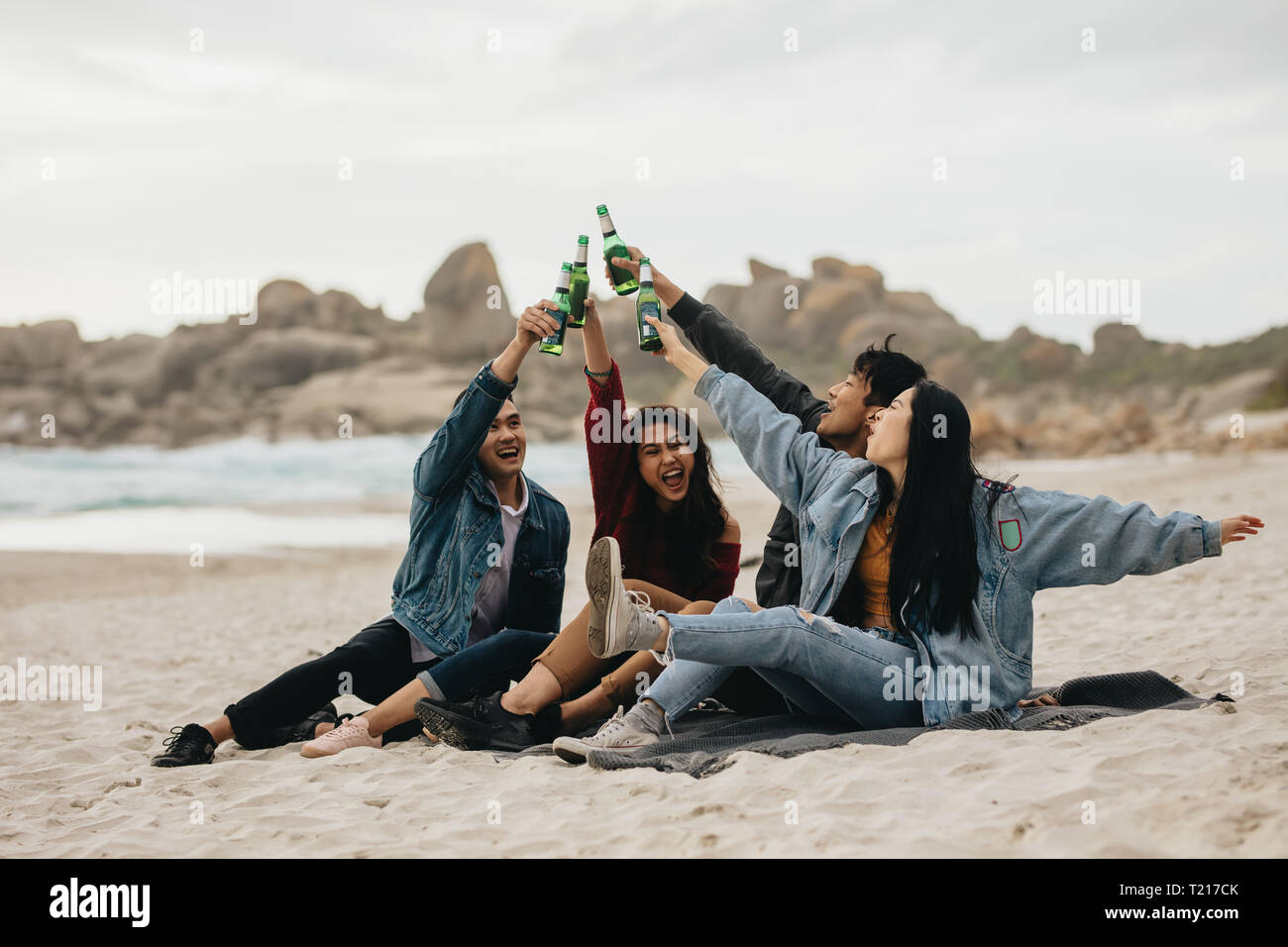Quatre amis asiatique excité toasting beer sur la plage. Les jeunes gens sur la plage ayant une partie avec des boissons. Banque D'Images