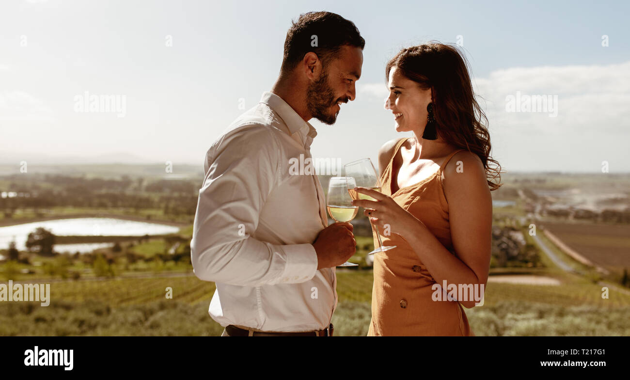 Close up of a romantic couple standing proches l'un de l'autre tenant un verre de vin. Couple heureux de passer du temps ensemble sur une date. Banque D'Images