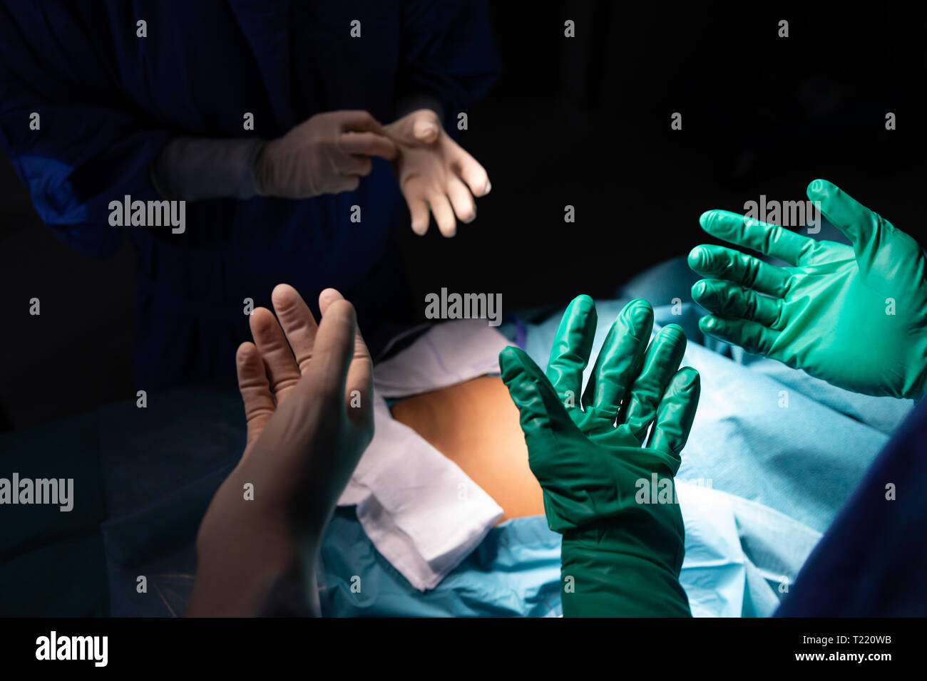 Chirurgiens portant des gants chirurgicaux en salle d'opération Banque D'Images