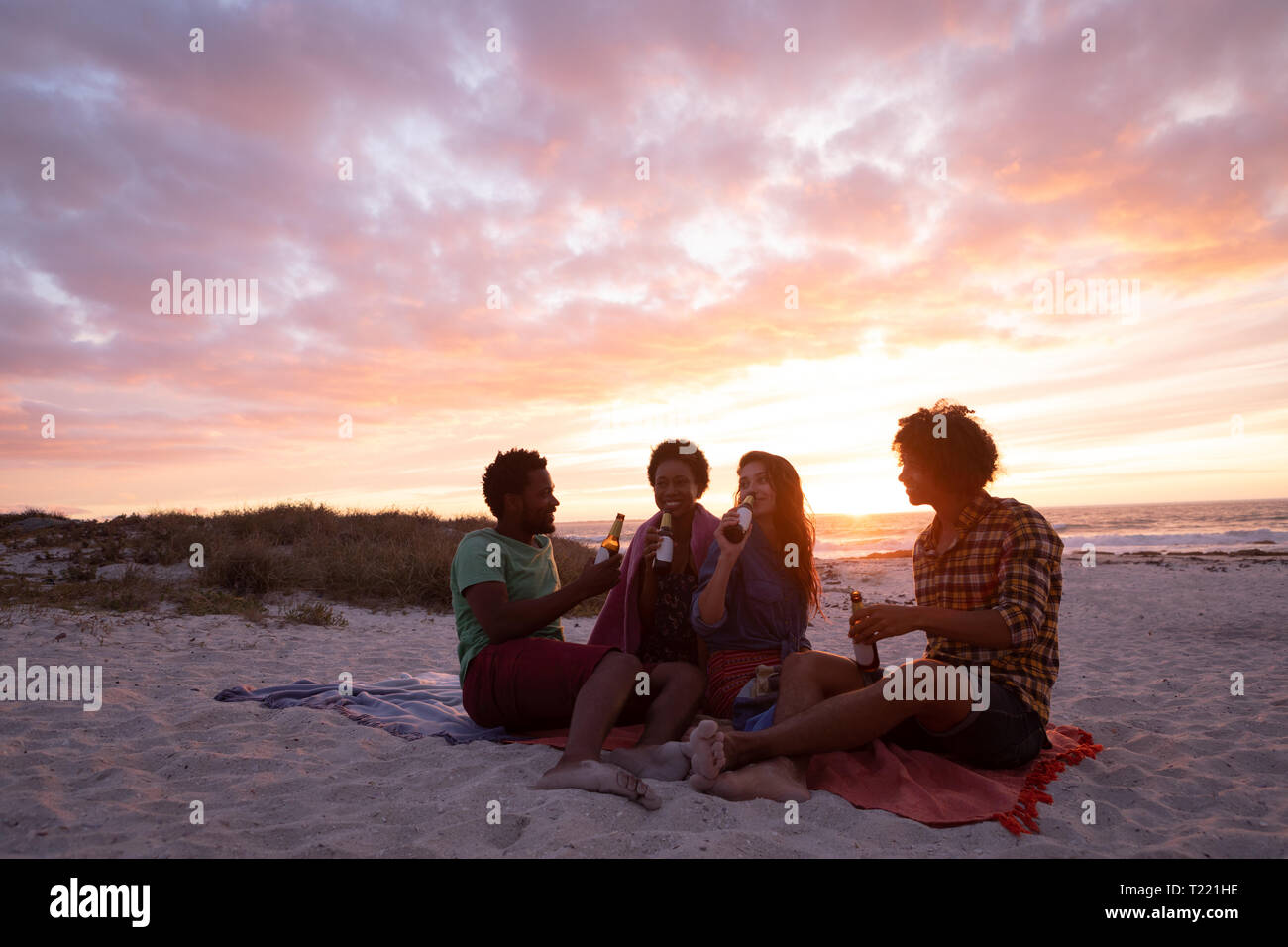 Groupe d'amis en interaction les uns avec les autres tout en ayant de la bière au beach Banque D'Images