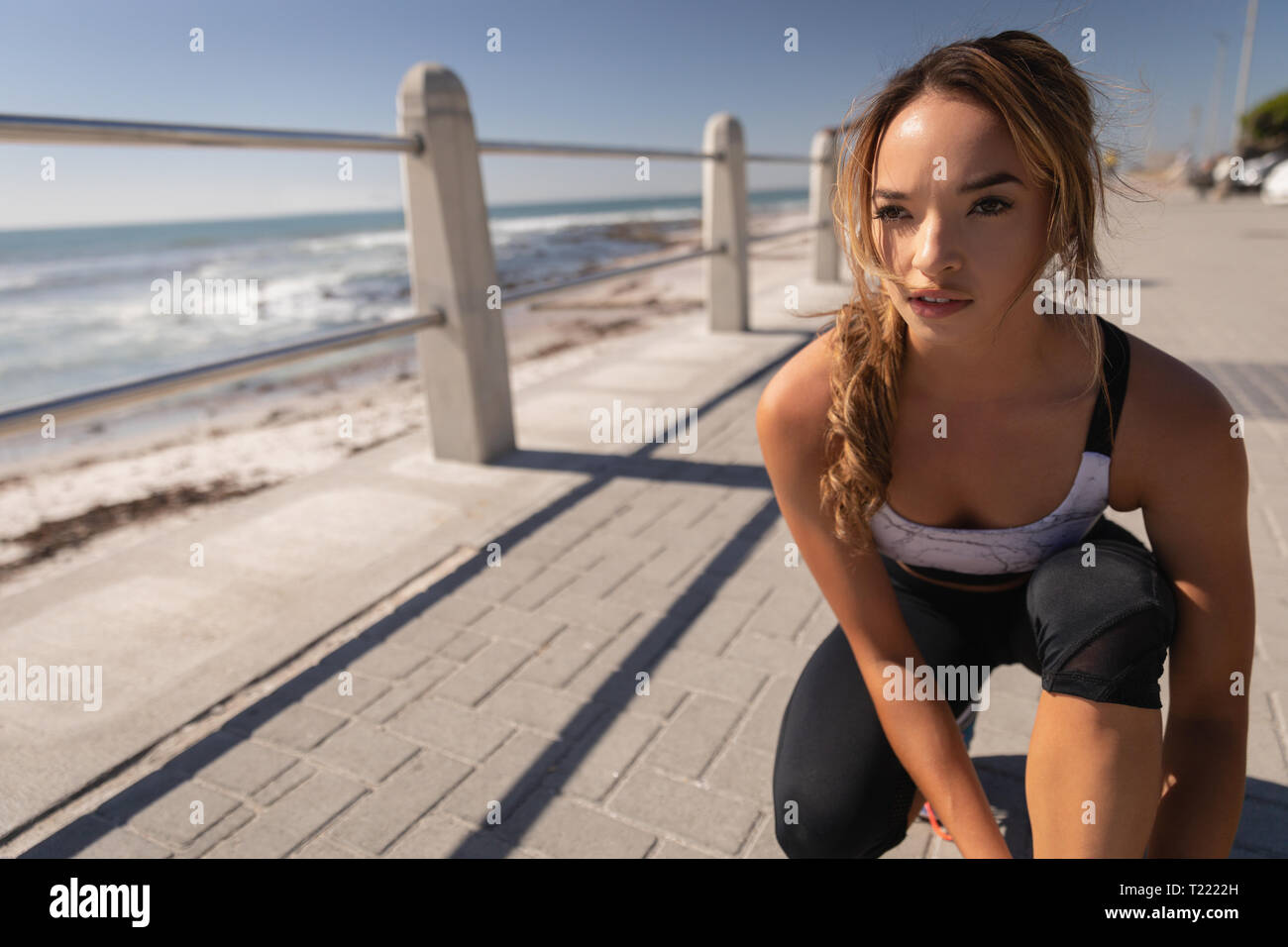 Belle femme lacet attachant sur le pavé à la promenade beach Banque D'Images