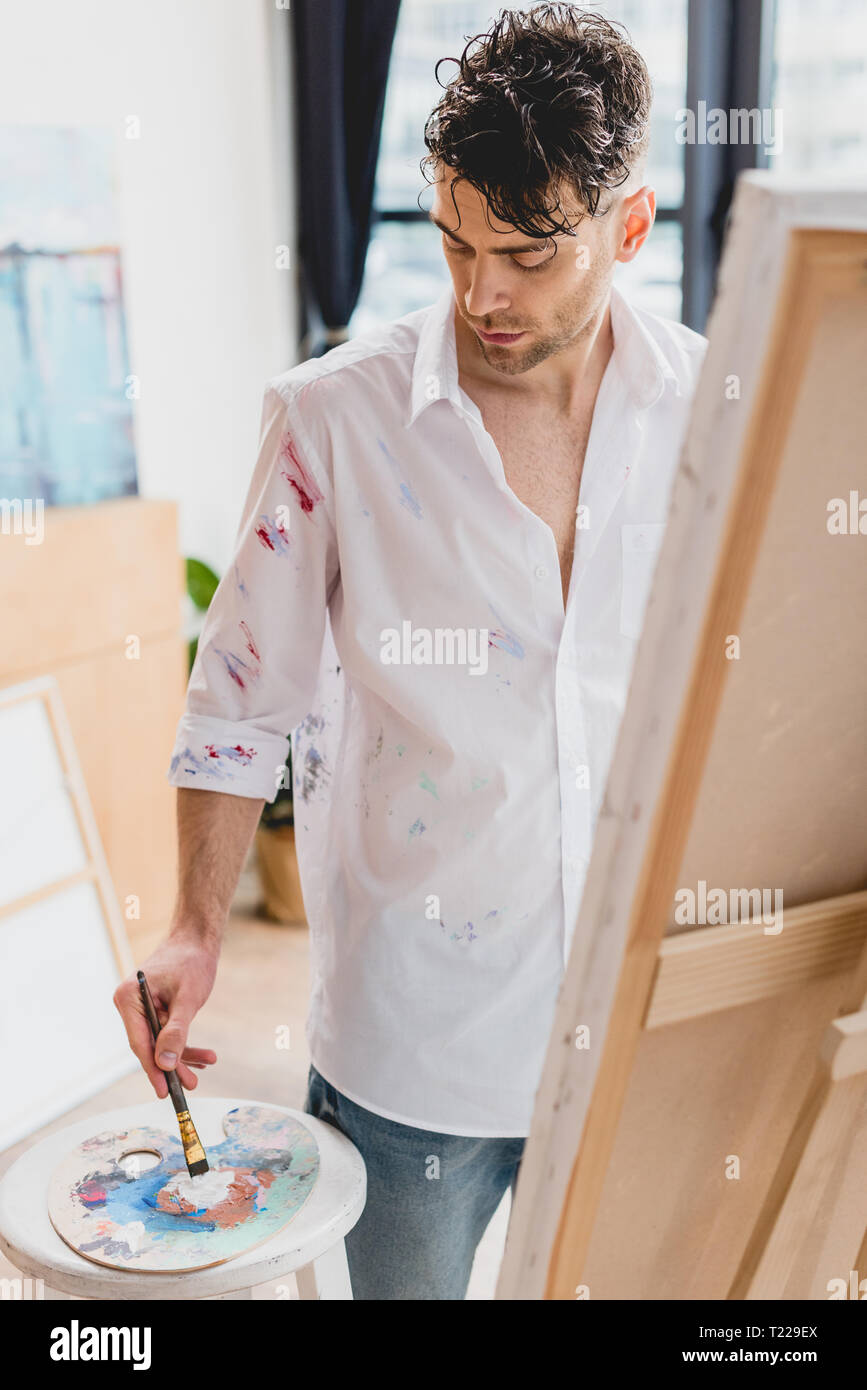 Portrait de l'artiste en chemise blanche tachetée de peinture mélange des  peintures sur palette Photo Stock - Alamy