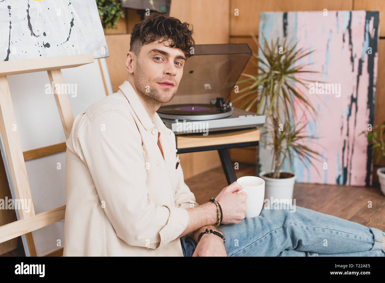 Artiste beau holding Coffee cup alors qu'il était assis près de vinyl record player Banque D'Images