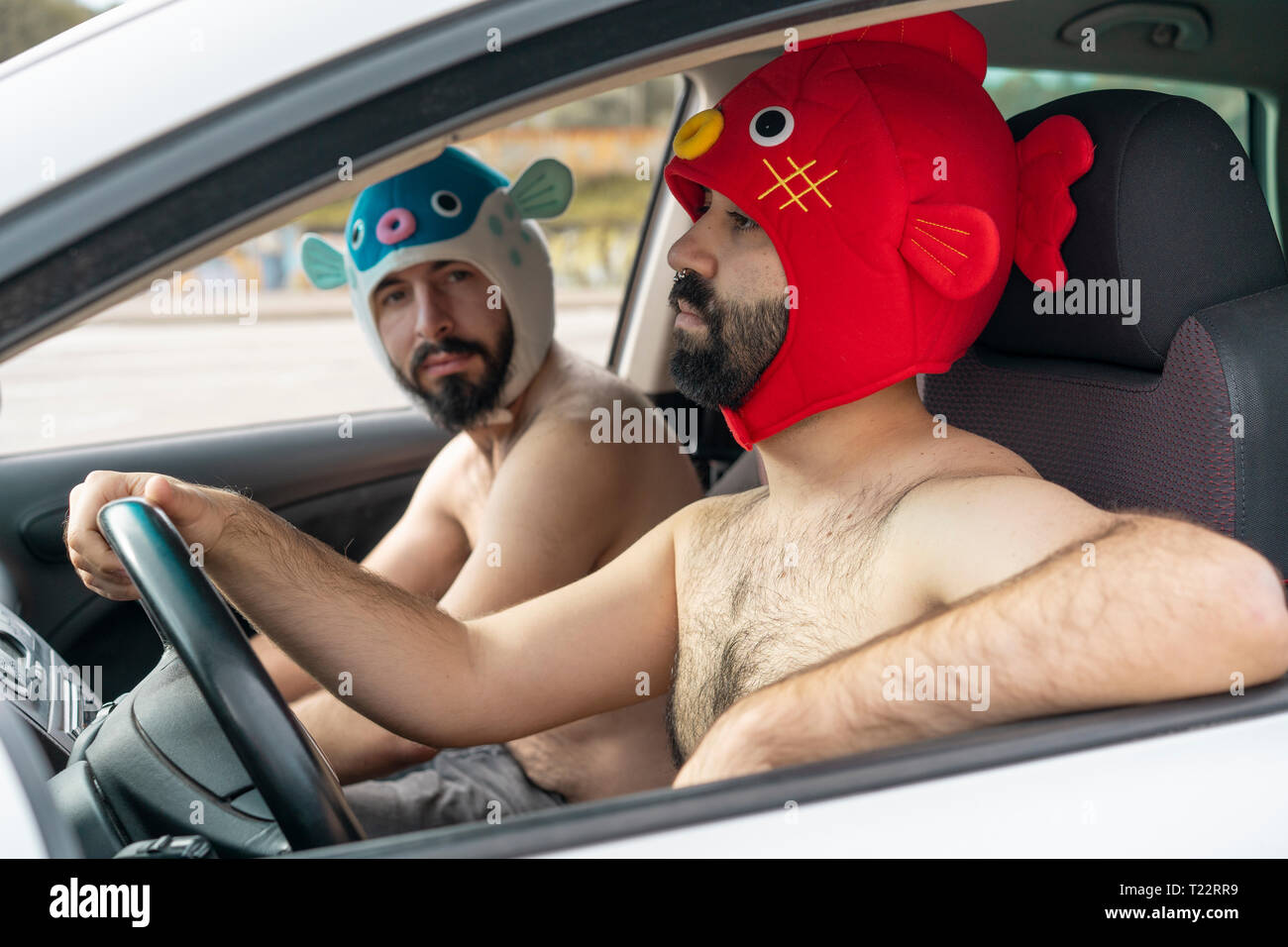 Couple gay dans une voiture portant des chapeaux d'animaux Banque D'Images