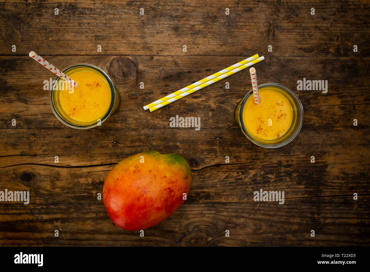 Mangue et deux verres de lassi à la mangue avec curcuma et pailles sur bois Banque D'Images