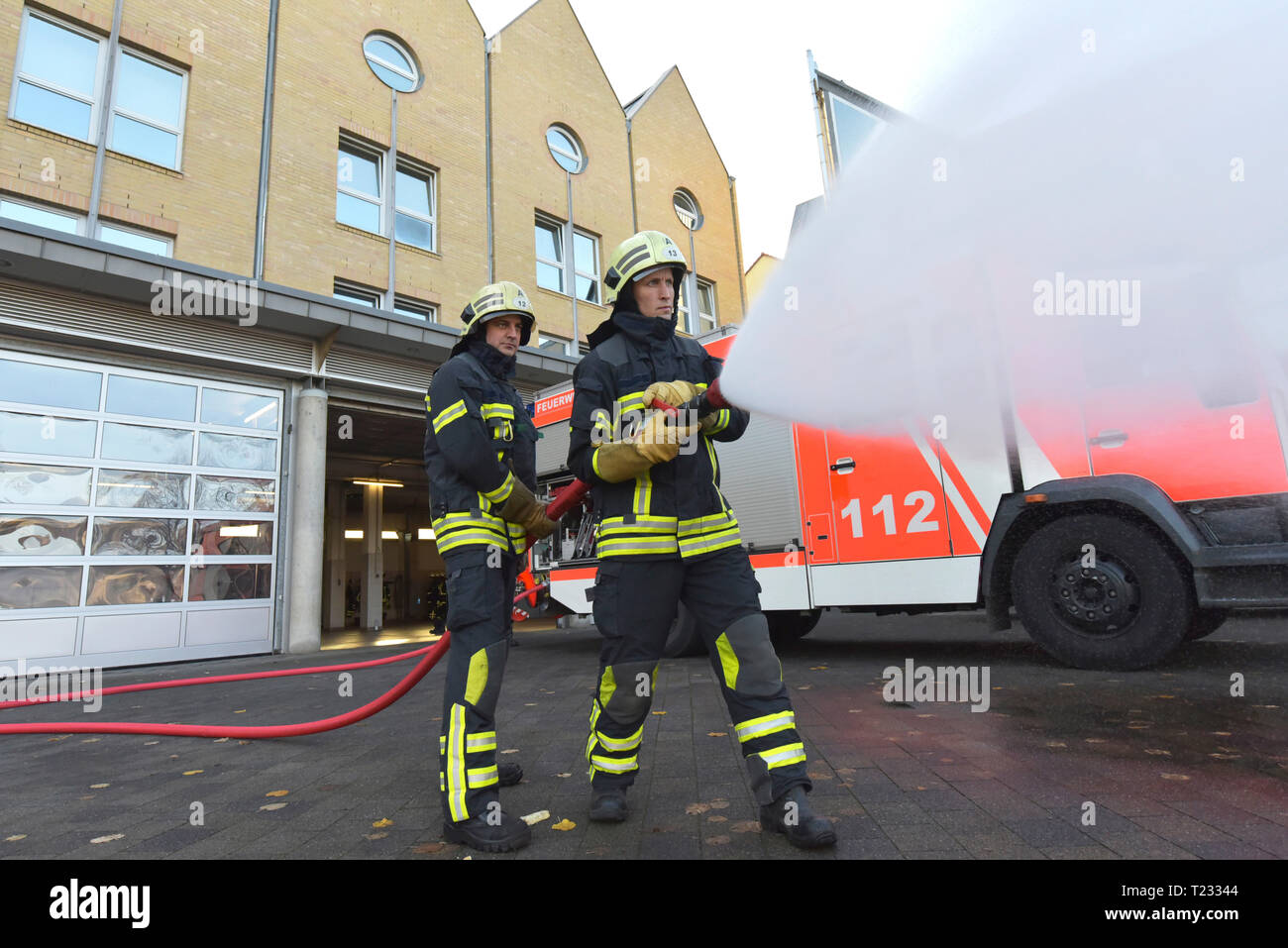 Deux pompiers debout sur l'eau d'extinction de l'exercice avec cour Banque D'Images