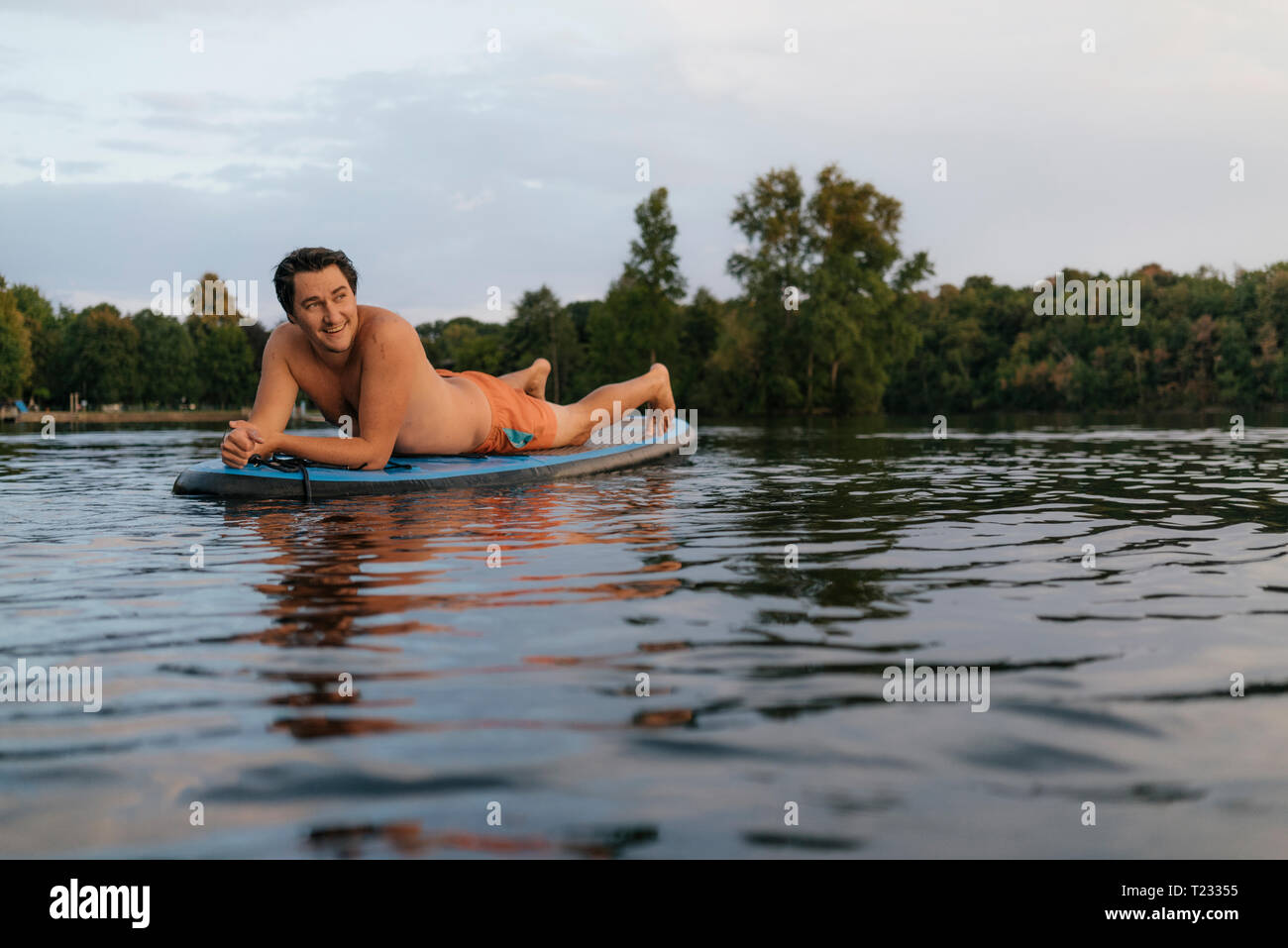 Homme étendu sur le SUP board sur un lac Banque D'Images