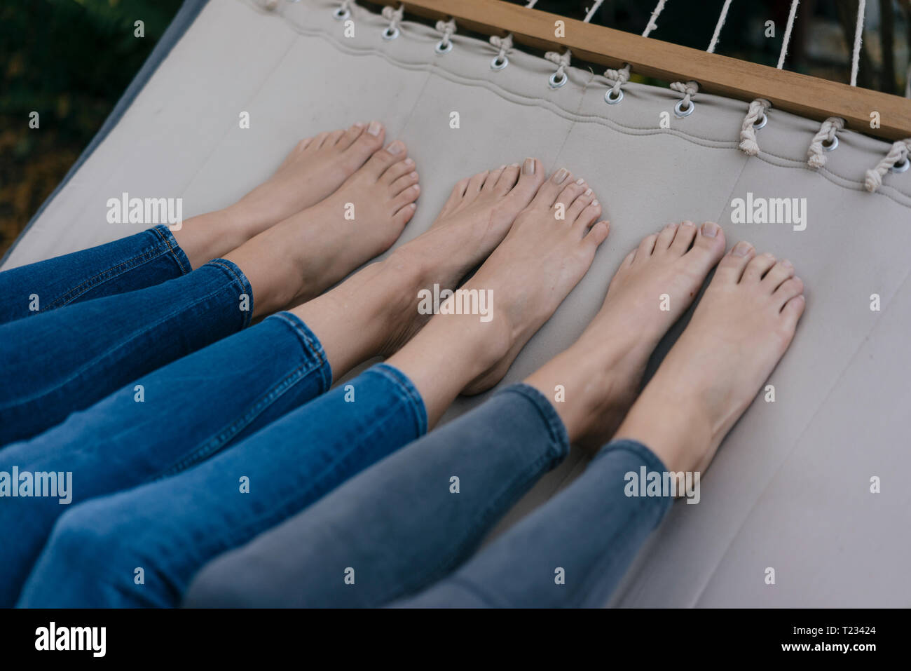 Pieds de trois femelles couché dans un hamac dans le jardin Banque D'Images