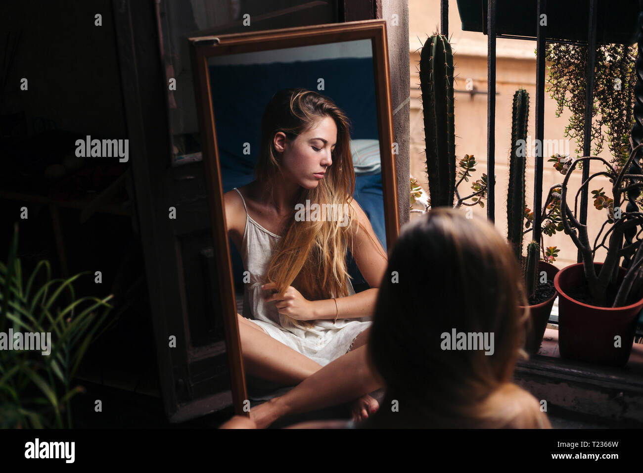 Image miroir de jeune femme assise sur le sol à se détendre Banque D'Images