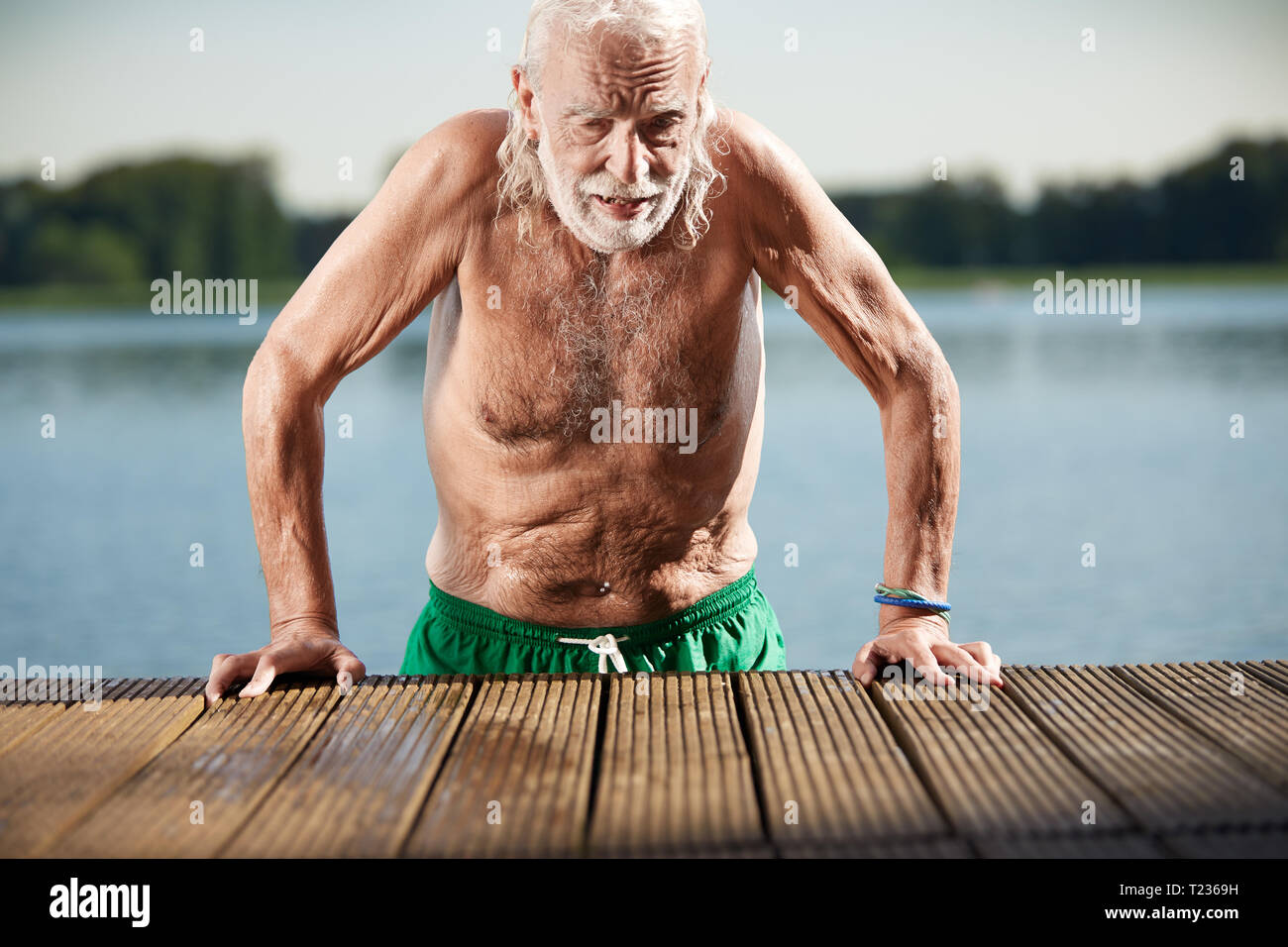 Portrait of senior man leaning on jetty at Lake Banque D'Images