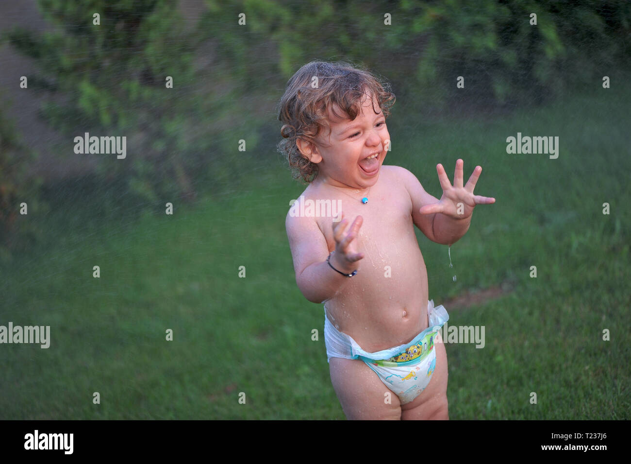 Bébé se mettre à l'eau sur un jardin en été Banque D'Images