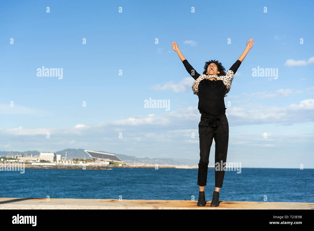 Espagne, Barcelone, la femme vêtue de noir debout sur le mur en criant de joie Banque D'Images