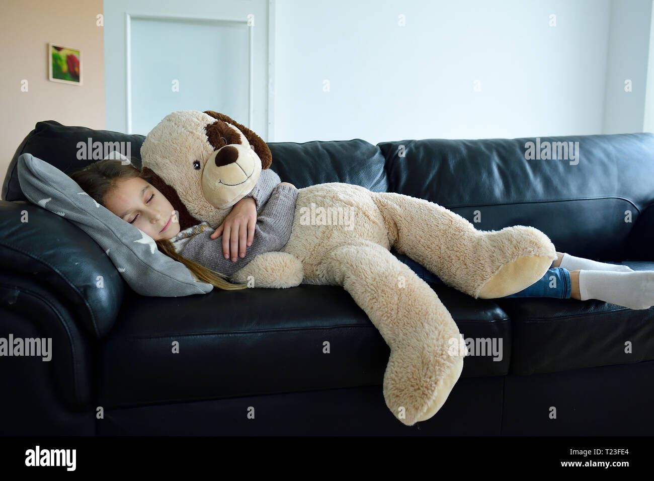 Girl relaxing on couch with oversized soft toy Banque D'Images