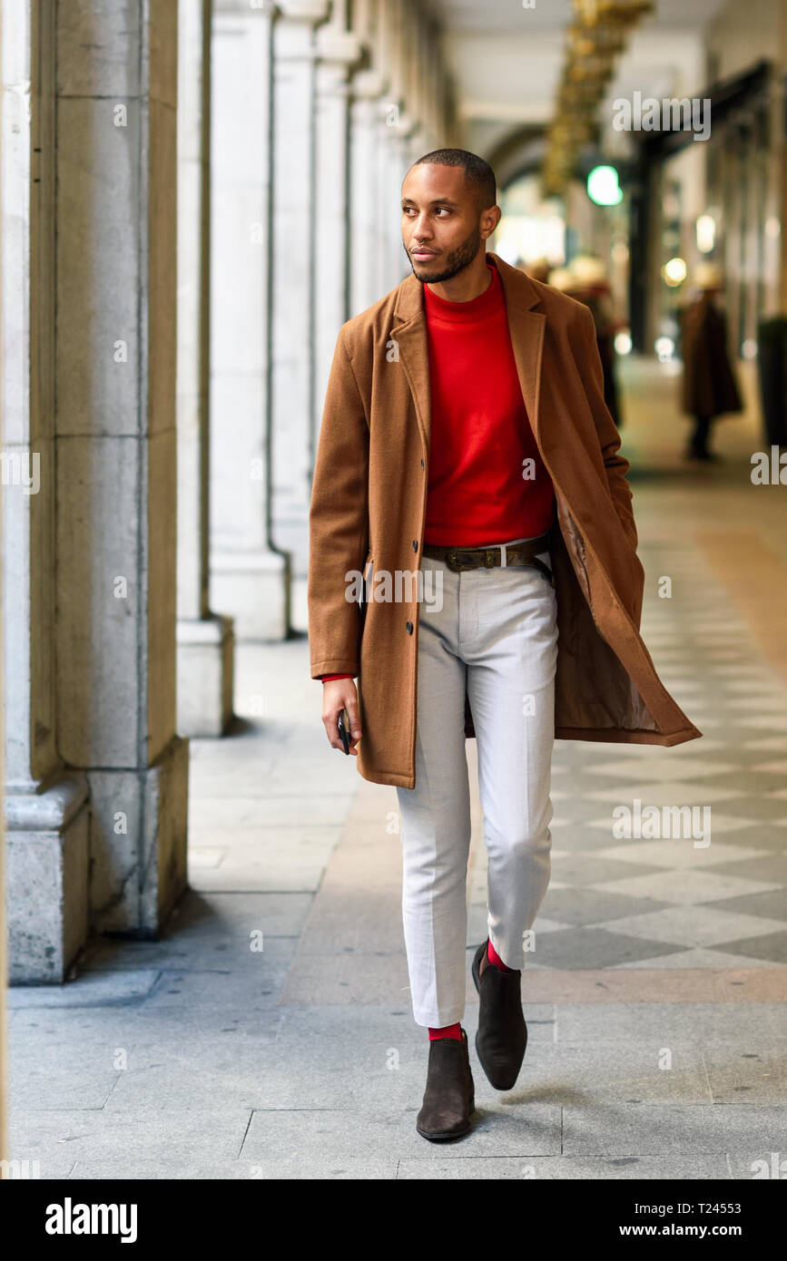 Jeune homme portant à la mode pull rouge et marcher le long de la couche  brune arcade Photo Stock - Alamy