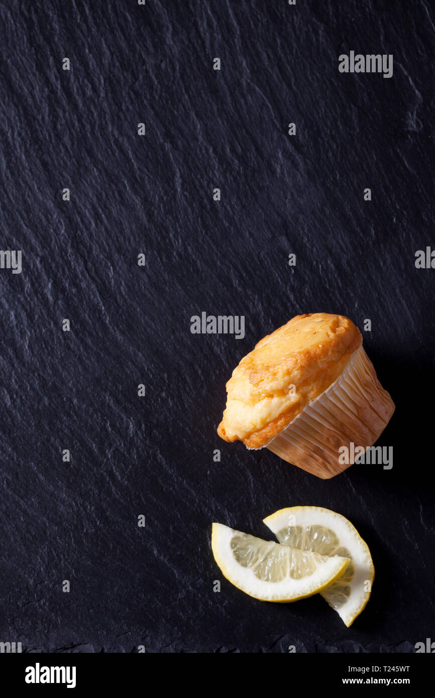 Muffin citron frais sur l'ardoise noire avec les tranches de citron Banque D'Images