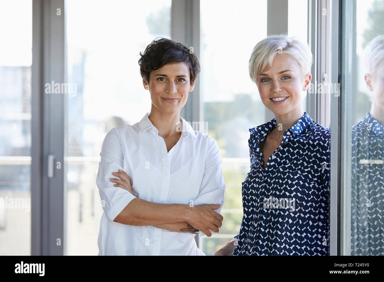 Portrait de deux femmes à la fenêtre smiling in office Banque D'Images