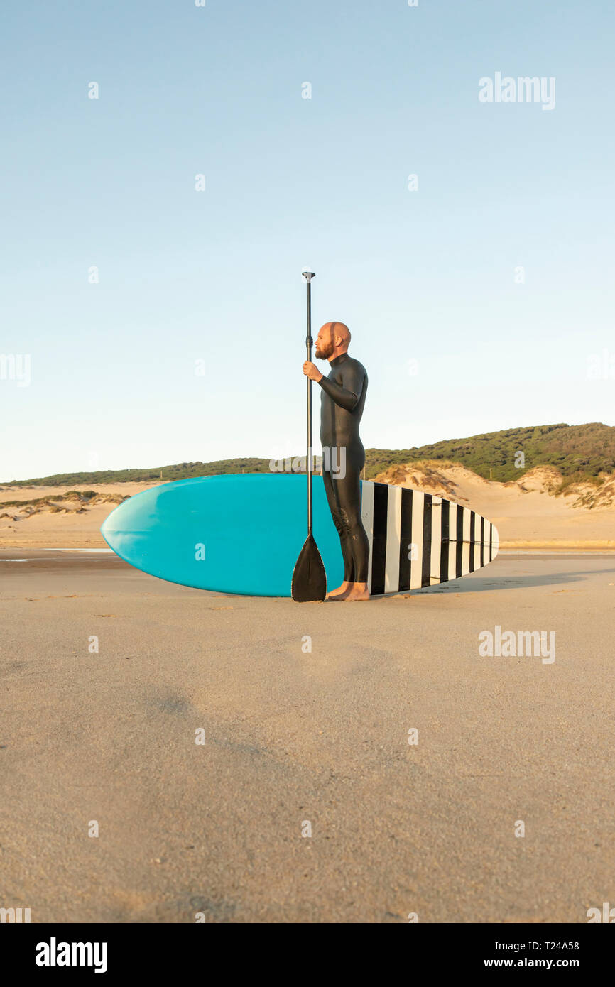 Espagne, Andalousie, Tarifa, l'homme avec stand up paddle board sur la plage Banque D'Images
