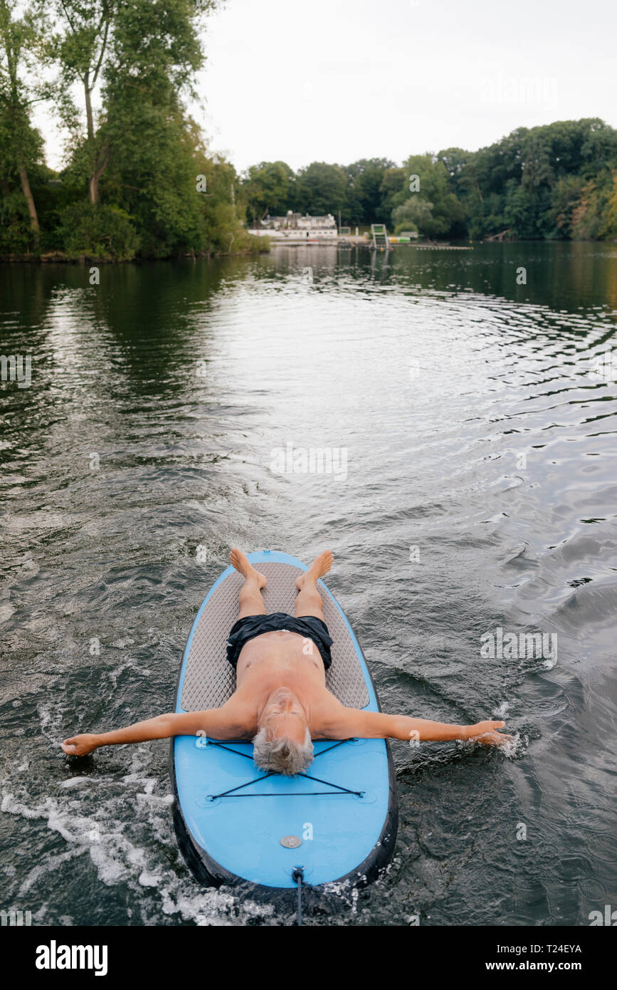 Man lying on SUP board sur un lac Banque D'Images